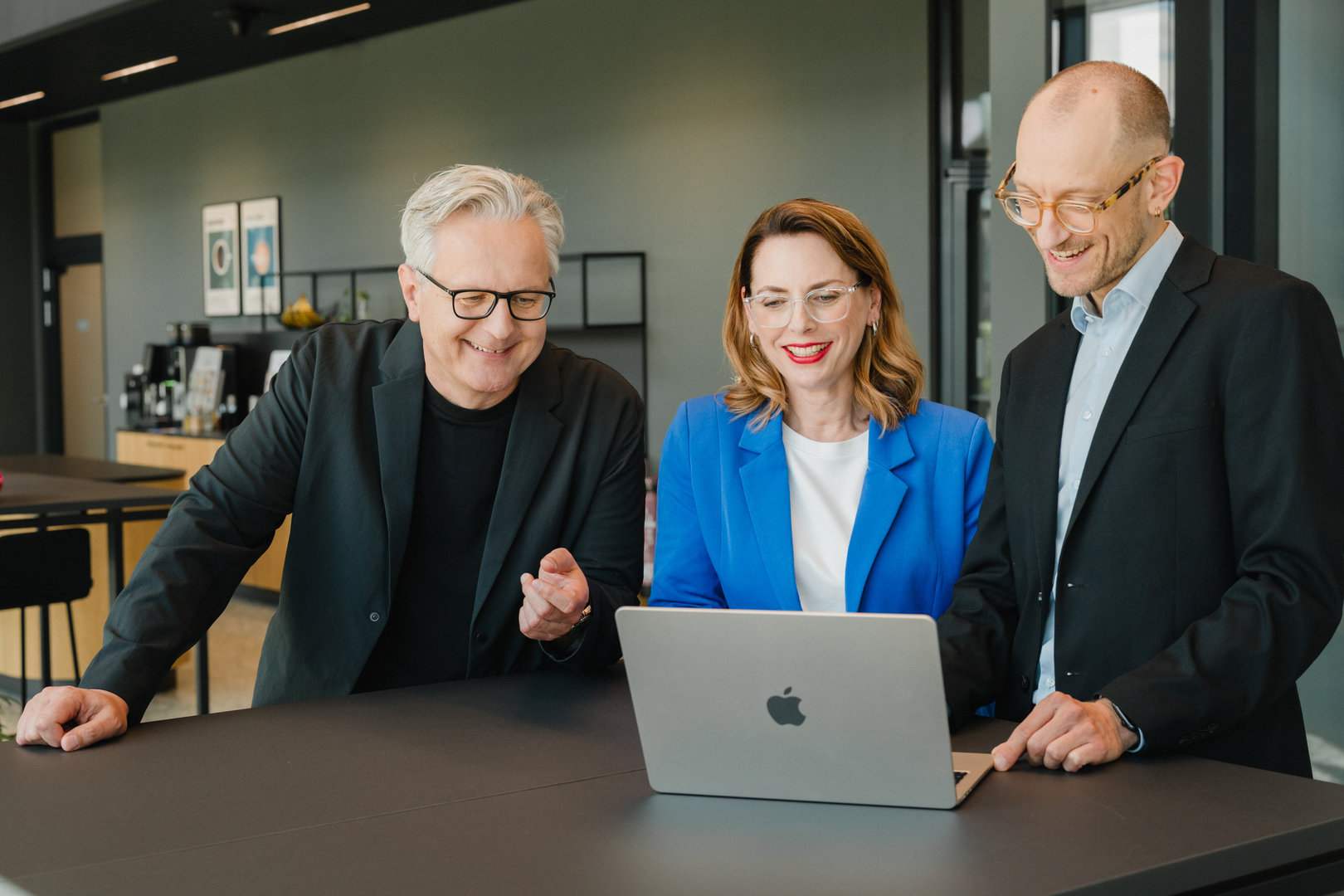 Drei Mitarbeitende von Experience Media im gemeinsamen Austausch an einem Laptop während einer technischen Abstimmung.